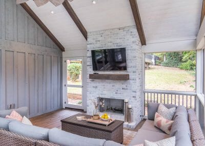 Seating area and fireplace with mantel and TV in screened porch remodel in East Cobb