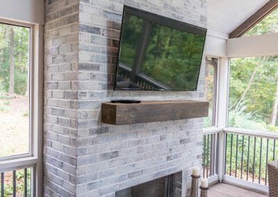 Gas fireplace with mantel and TV in screened porch remodel in East Cobb