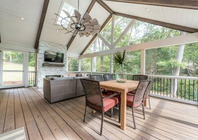 Dining area, seating area and fireplace with TV in screened porch addition in East Cobb