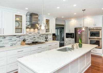 Island, ovens and cooktop view in white kitchen remodel in Sandy Springs