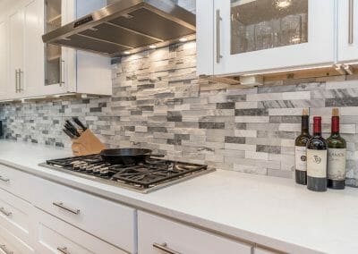 Decorative tile backsplash and cooktop with hood vent in kitchen remodel in Sandy Springs