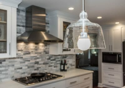 View of light fixture and cooktop with tile backsplash in open kitchen remodel is Sandy Springs