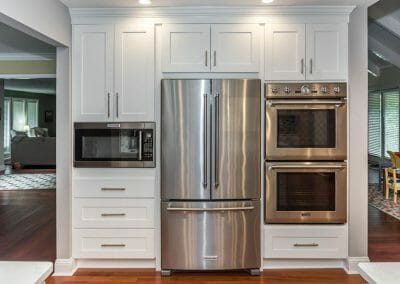 Double ovens and built-in microwave flanking French door fridge in kitchen remodel in Sandy Springs