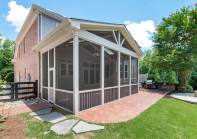 Porch renovation with view from yard, with custom screening, vaulted ceiling, recessed lights, faux beams, skylights, gable pediment design, and handrail on existing herringbone brick patio.