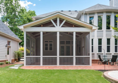 Porch renovation with view from yard (centered), with 15 foot height, vaulted ceiling with recessed lights, custom screens, and gable pediment design on existing brick patio.