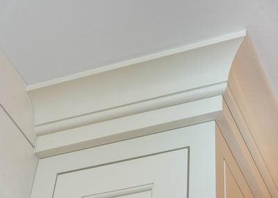 Kitchen renovation detail of multi-piece crown molding and custom, flush-set cabinet doors.