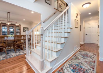 Custom stairway renovation with whitewashed oak treads, newel posts, and handrails.