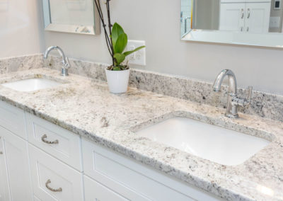 Bathroom double-sink vanity with chrome faucet fixtures and granite countertop.