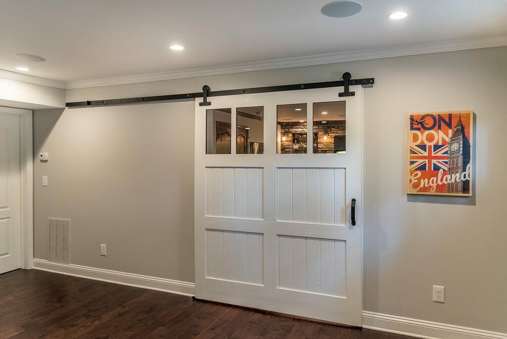 The barn door separates the bar and home theater in entertainment space in East Cobb