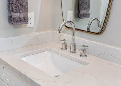 Master bath renovation detail of vanity sink with marble countertop and chrome fixture.