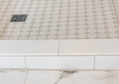 Master bath renovation detail of 12x24 marble tile floor, subway tile shower curb, and mosaic tile shower pan.