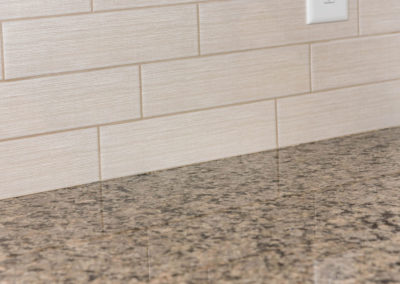Kitchen renovation detail of textured subway backsplash tile and granite countertop.