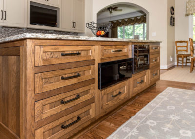 Kitchen renovation detail of island custom flush-set cabinetry, microwave, warming oven, granite countertop, and hardwood floors.