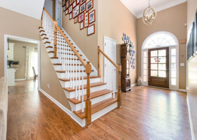 Renovated staircase with new oak newel posts and handrail with white balusters; note widened ADA-compliant doorway to left (now a 40 inch opening).