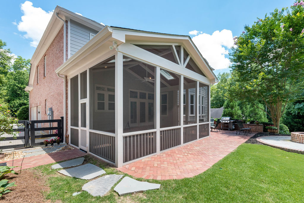 Porch renovation with view from yard, with custom screening, vaulted ceiling, recessed lights, faux beams, skylights, gable pediment design, and handrail on existing herringbone brick patio.