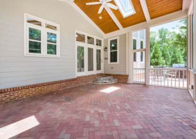 Porch renovation with custom screening, vaulted ceiling, recessed lights, faux beams, skylights, and handrail on existing herringbone brick patio.