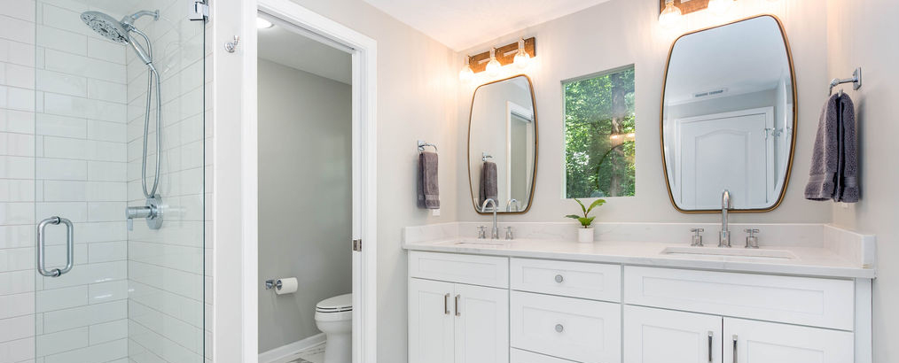 Master bath renovation with 12x24 marble tile floor, glass-walled shower, double vanity with marble countertop, and pocket door to the water closet.