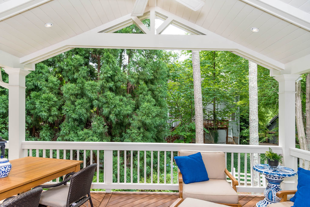 Porch renovation with view from porch of railings, crowned corner posts, vaulted tongue and groove ceiling, recessed lighting, exposed beams, and custom gable pediment design.