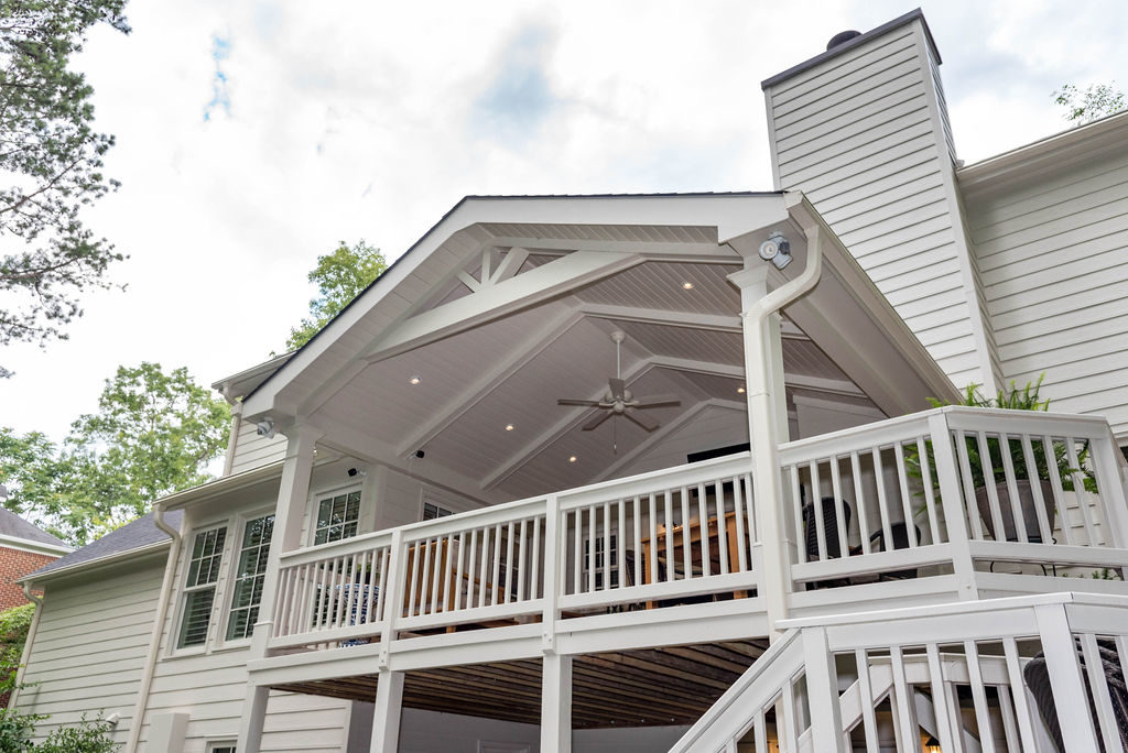 Porch renovation with view from yard of railings, crowned corner posts, vaulted tongue and groove ceiling, recessed lighting, expose beams, and custom gable pediment design.