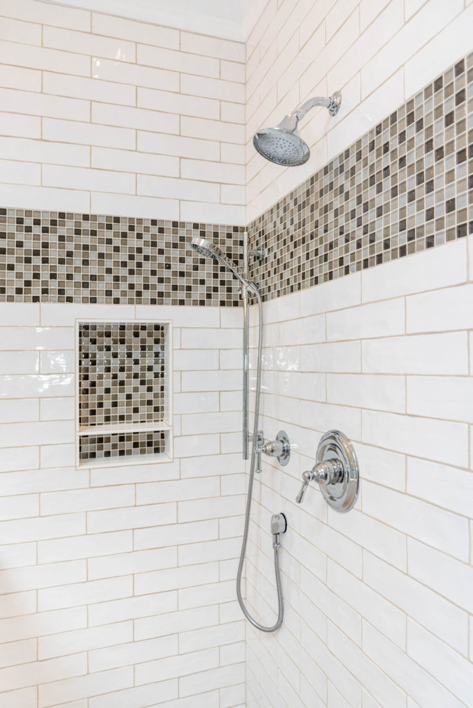 Shower with wavy white subway tile (2.5"x8") and 12" glass mosaic band.